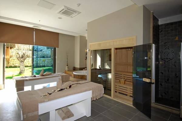Behandlungsraum im Commodore Elite Suites & Spa mit zwei Massageliegen, Sauna und Badewanne.