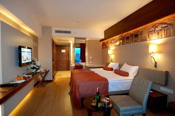 Ein modernes Hotelzimmer im Commodore Elite Suites & Spa mit zwei Betten, Fernseher und Nachttisch.