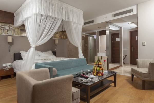 Schlafzimmer im Commodore Elite Suites & Spa mit Bett, Couch, Tisch und Früchten.