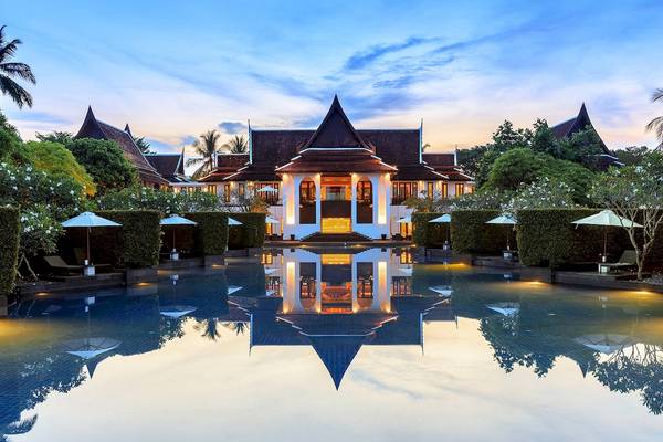 JW Marriott Khao Lak Resort & Spa bei Sonnenuntergang mit Pool und umliegenden Bäumen und Sonnenschirmen.