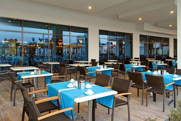 Restaurant des Commodore Elite Suites & Spa mit blauen Tischdecken und großen Fenstern.
