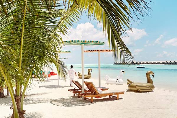 Luxuriöse Strandszene am LUX South Ari Atoll mit Palmen, Liegestühlen und Schlauchbooten