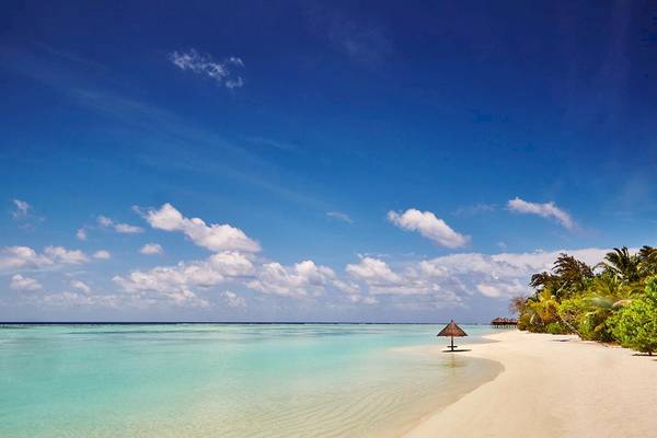 Strand des LUX South Ari Atoll Hotels mit blauem Himmel und kristallklarem Wasser