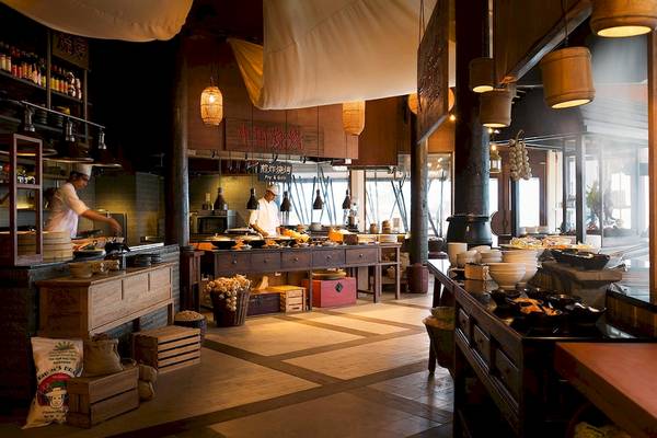 Innenansicht des Restaurants im LUX South Ari Atoll Hotel mit Köchen, die Speisen zubereiten, und vielen Gerichten, die serviert werden.