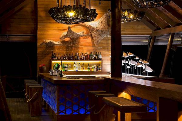 Bar im LUX South Ari Atoll Hotel mit Holztheke und blauer Beleuchtung.