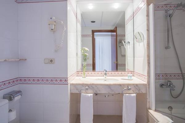 Badezimmer im Hipotels Said Hotel mit weißem Waschbecken, Spiegel und Handtüchern.