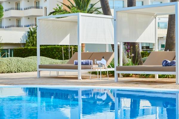 Pool-Lounge-Bereich im Hipotels Said mit zwei weißen Sonnenliegen und Überdachungen.