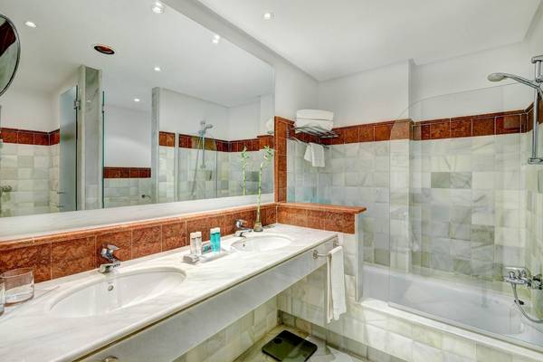 Badezimmer des Hipotels Said mit zwei Waschbecken, Badewanne und Dusche.