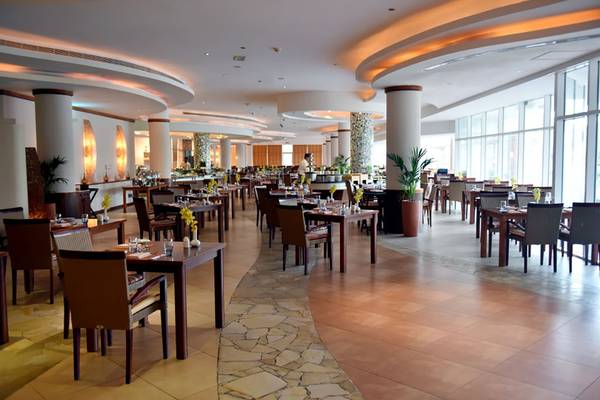 Innenansicht des Restaurants im Fujairah Rotana Resort & Spa mit gedeckten Tischen und eleganter Einrichtung.