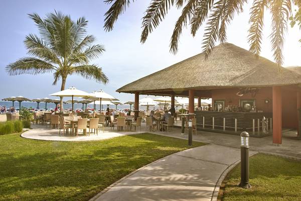 Strandcafe des Fujairah Rotana Resort & Spa mit Gästen und Palmen