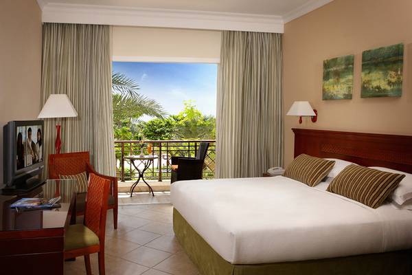 Hotelzimmer im Fujairah Rotana Resort & Spa mit Balkon, Fernseher und Möbeln.