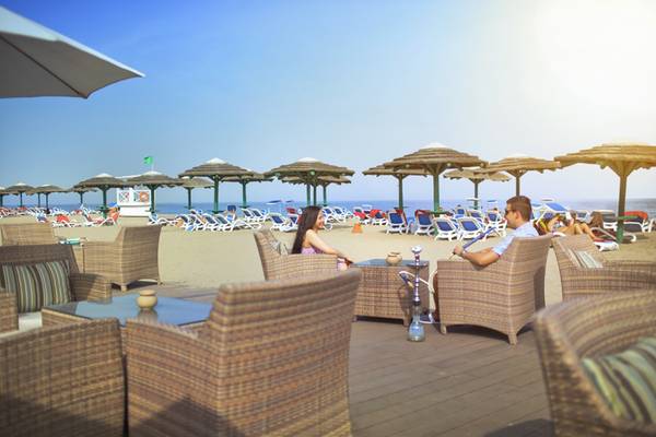 Paar sitzt in der Strandbar des Fujairah Rotana Resort & Spa mit Blick auf den Strand