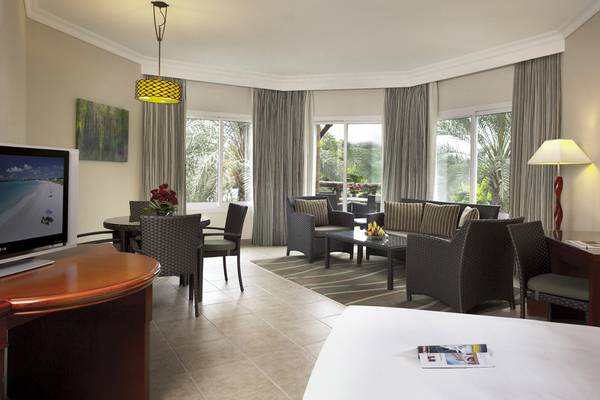 Innenansicht einer Hotelsuite mit Wohnzimmer, Essbereich und Fernseher.