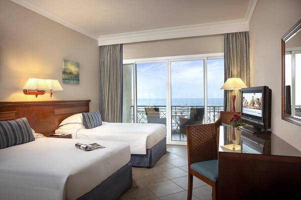 Zwei Betten im Hotelzimmer des Fujairah Rotana Resort & Spa mit Balkon und Meerblick.