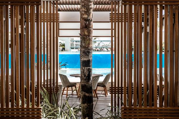 Terrasse des Avra Imperial Hotels mit Tisch und Stühlen, Blick auf den Pool.