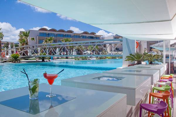 Barbereich am Pool des Avra Imperial Hotels mit bunten Stühlen und Cocktails.