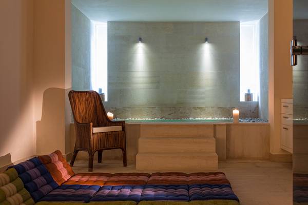 Wellnessbereich im Avra Imperial Hotel mit Badewanne, Kerzen und Sitzmöbeln.