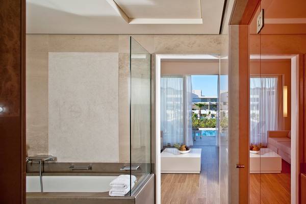 Badezimmer mit Badewanne und Aussicht auf den Pool im Avra Imperial Hotel
