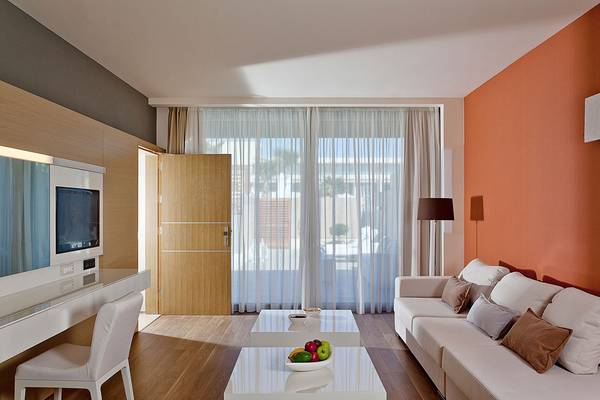 Innenraum des Avra Imperial Hotels mit modernem Design, Fernseher und offenem Fenster.
