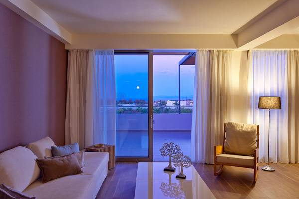Wohnbereich im Avra Imperial Hotel mit großer Glastür und Aussicht auf den Mond.