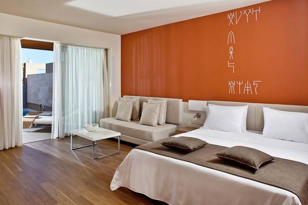 Hotelzimmer mit orange Wand und Bett von Avra Imperial