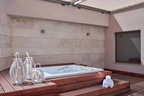 Outdoor-Jacuzzi im Avra Imperial Hotel mit weißen Laternen und Holzdeck.