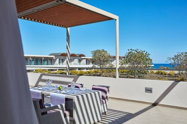 Balkon mit Meerblick im Avra Imperial Hotel mit Tisch und Stühlen unter einer Pergola.