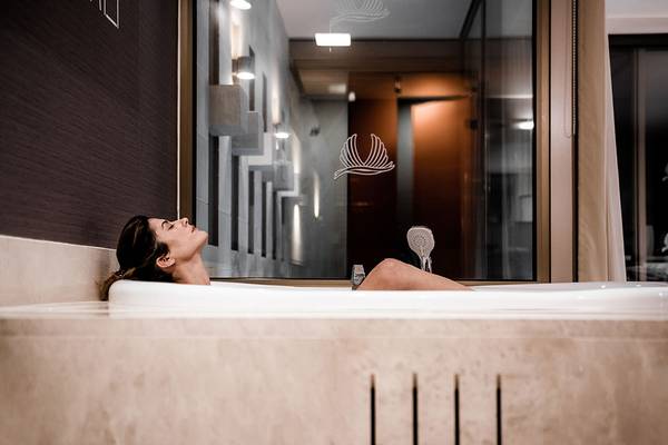 Eine Frau entspannt sich in der Badewanne des Avra Imperial Hotels.