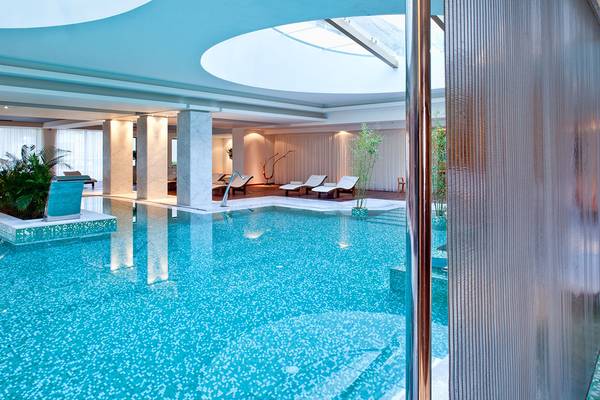 Innenpool im Avra Imperial Hotel mit weißen Säulen und Liegestühlen