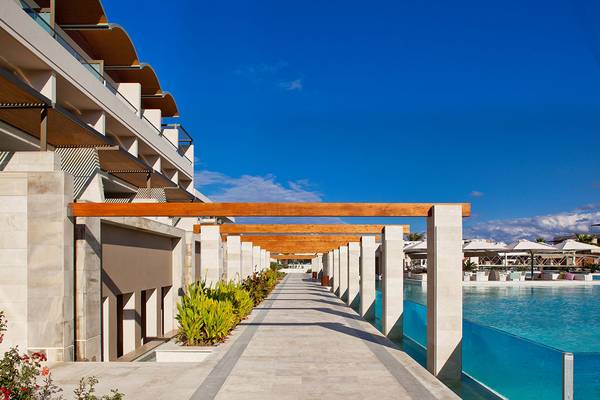Außenansicht des Avra Imperial Hotels mit Pool und Gehweg.