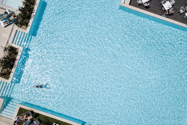 Oberflächenansicht des Schwimmbeckens im Avra Imperial Hotel mit mehreren Personen, die sich entspannen.