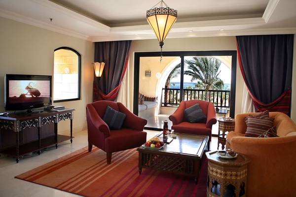 Wohnzimmer des Pickalbatros The Palace Port Ghalib mit zwei roten Sesseln, einem orangefarbenen Sofa und einem Fernseher.