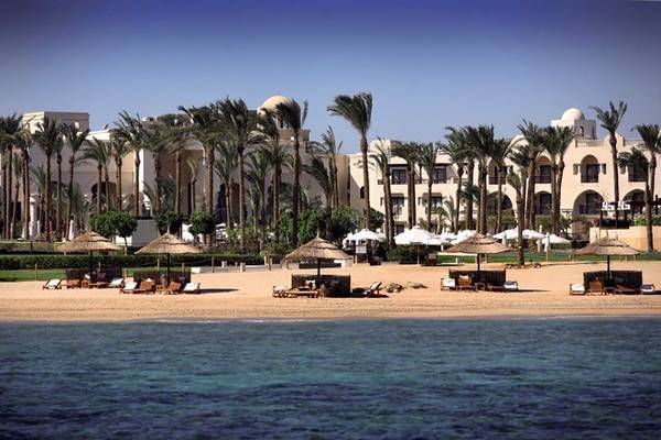 Außenansicht des Pickalbatros The Palace Port Ghalib Hotels mit Strand und Sonnenschirmen.