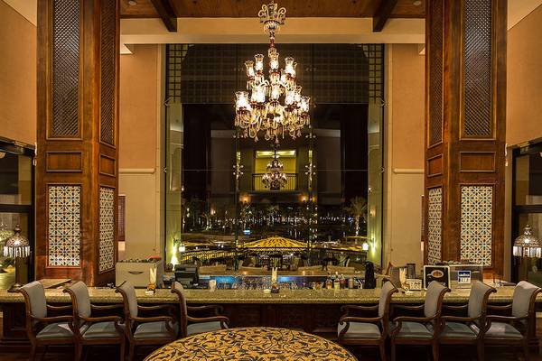 Innenansicht der Bar im Pickalbatros The Palace Port Ghalib Hotel mit großem Kronleuchter, Sitzbereich und Blick auf die Nachtlandschaft.