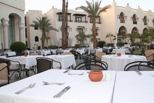 Außenbereich des Pickalbatros The Palace Port Ghalib Hotels mit vielen gedeckten Tischen und Stühle.