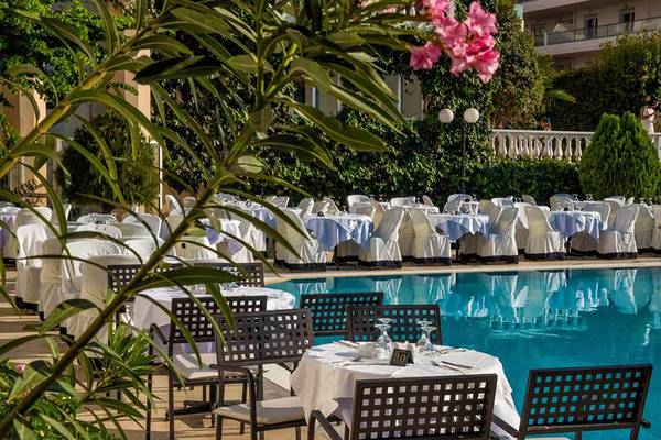 Pool-Essbereich des Hersonissos Palace Hotels mit gedeckten Tischen und Stühlen.