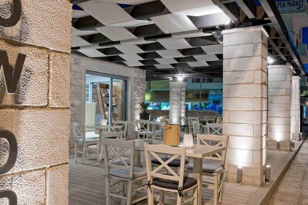 Außenbereich des Hersonissos Palace Hotels mit beleuchteten Säulen und Tischplätzen.