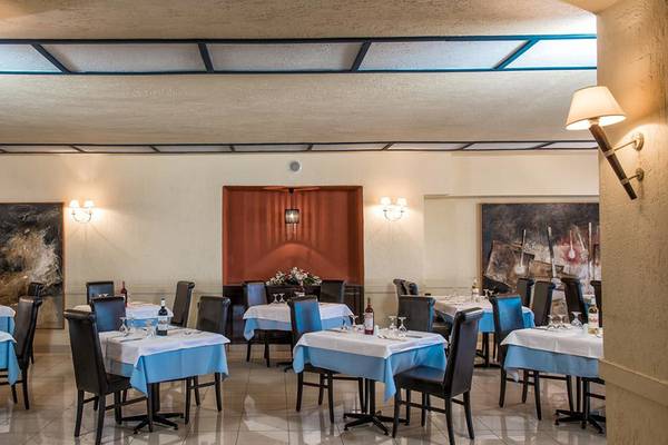 Innenansicht des Restaurants im Hersonissos Palace Hotel mit blauen Tischdecken und dunklen Stühlen.