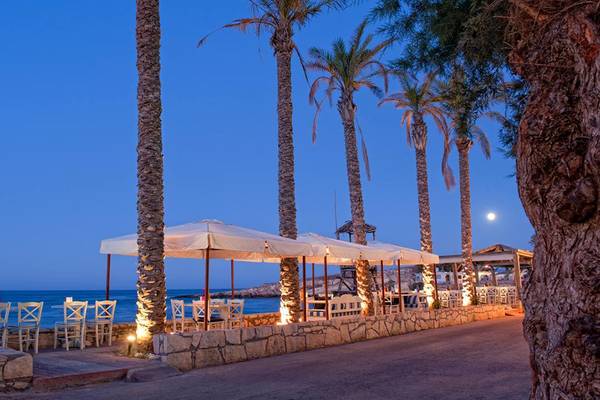 Strandbar des Hersonissos Palace Hotels bei Abend mit Palmen und Meer im Hintergrund.