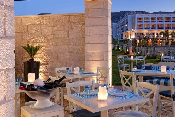 Außenbereich des Hersonissos Palace Hotels mit beleuchteten Tischen und Stühlen.