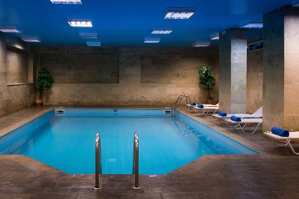 Innenpool im Hersonissos Palace Hotel mit blauen Kacheln und Lounge-Sesseln.