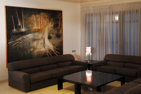 Wohnzimmer des Hersonissos Palace mit zwei Sofas, einem Tisch und einer großen Wandmalerei.