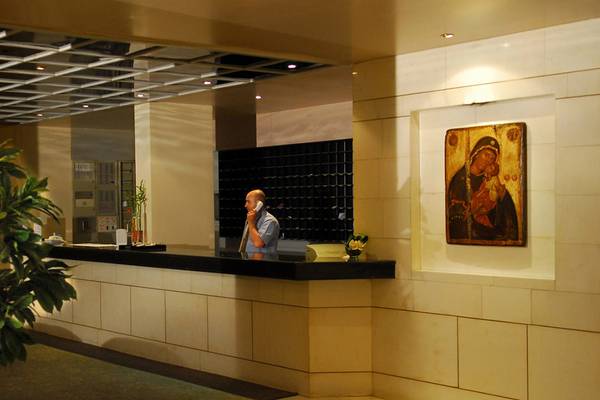 Mann telefoniert an der Rezeption des Hersonissos Palace Hotels, wo eine Ikone an der Wand hängt.