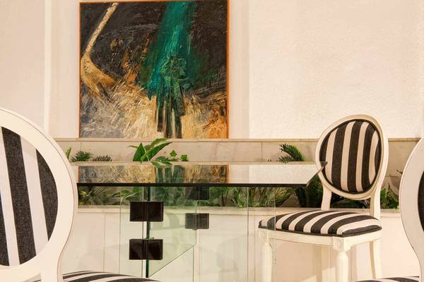Speisebereich im Hersonissos Palace mit modernen Stühlen und Glastisch, vor einer abstrakten Wandmalerei.