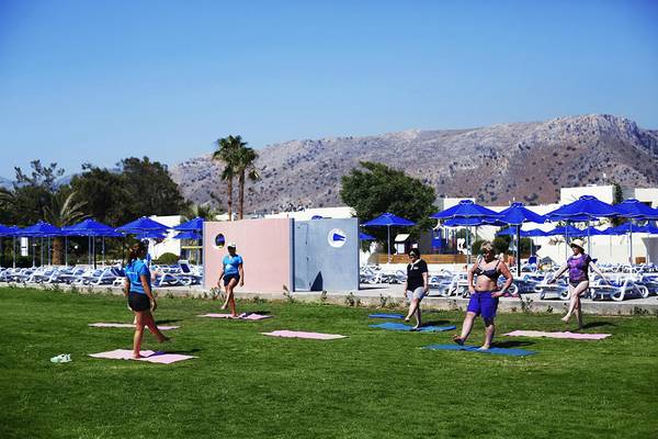 Gruppe von Frauen, die Yoga auf dem Rasen im Freien im Dessole Dolphin Bay Resort machen.