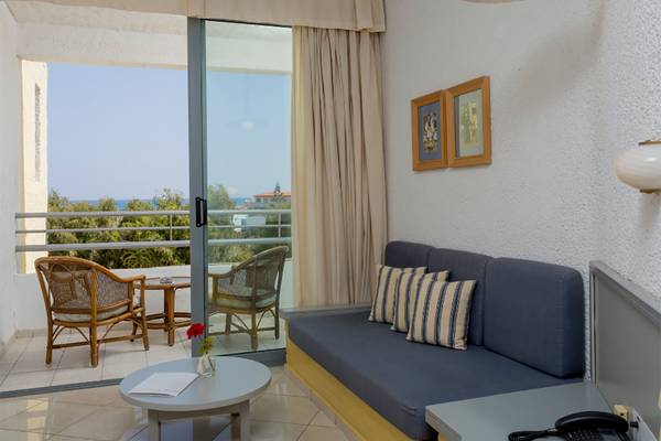 Hotelzimmer mit Balkon, Sofa, Tisch, Stühlen und Meerblick im Dessole Dolphin Bay Resort.