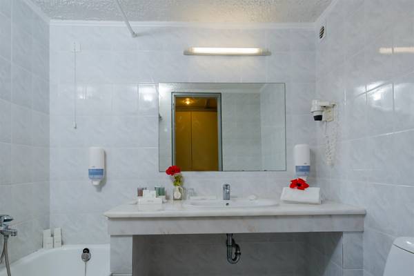 Ein Badezimmer mit weißem Waschbecken, Badewanne, Toilette und Spiegel im Dessole Dolphin Bay Resort.