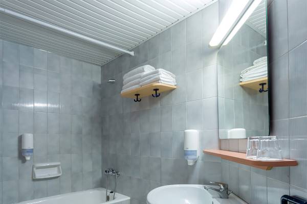 Badezimmer im Dessole Dolphin Bay Resort mit Badewanne, Waschbecken, Spiegel und Handtüchern