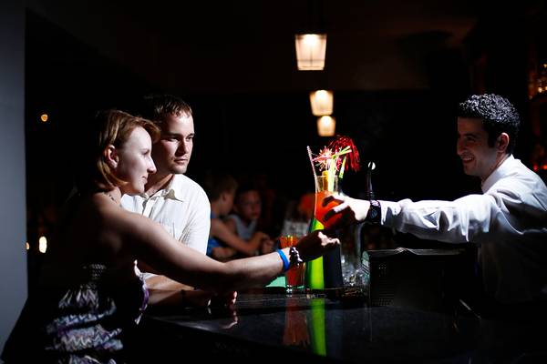 Besucher im Dessole Dolphin Bay Resort greifen nach einem Cocktail von einem Barkeeper.