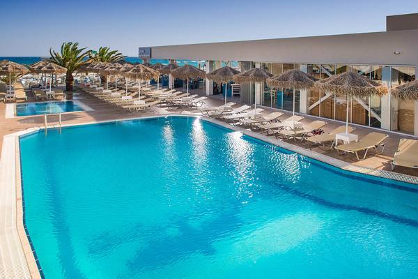 Poolbereich des Odyssia Beach Hotels mit Sonnenliegen und Sonnenschirmen.